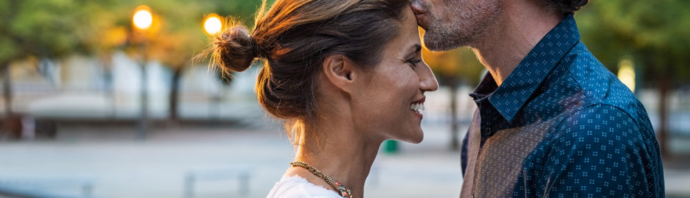 Mature husband kissing wife on forehead in the street in the eve